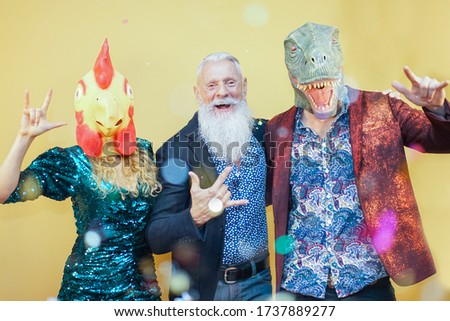 People dancing at carnival party wearing t-rex and chicken mask. Friends having fun listening rock music - Funny trend concept - Image