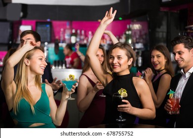 People are dancing with cocktails on the corporate event. 