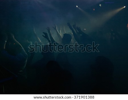 People dancing in the fog highlighted with night club lighting equipment