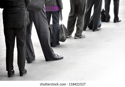 People In Dark Clothes With Bags Waiting In Queue