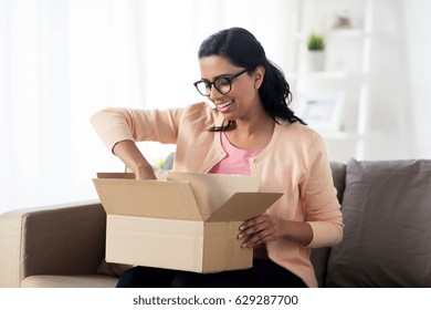 people, delivery, shipping and postal service concept - happy young indian woman holding open cardboard box or parcel at home
