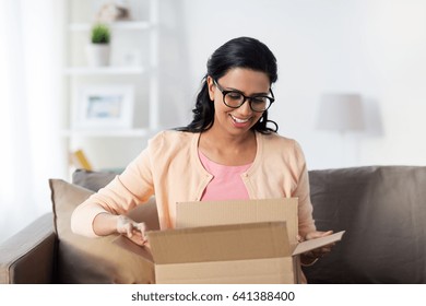 People, Delivery, Shipping And Postal Service Concept - Happy Young Indian Woman Holding Open Cardboard Box Or Parcel At Home