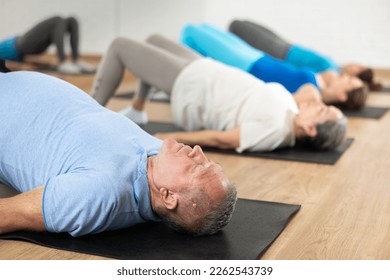 People of different ages performing glute bridge during group Pilates workout. Active lifestyle and wellness concept - Powered by Shutterstock