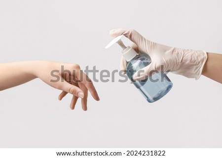 People disinfecting hands on light background