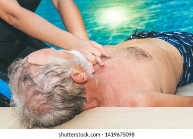 People are doing first aid by Cardiopulmonary Resuscitation or CPR to Old man with sudden cardiac arrest. During exercise with swimmimg together - Powered by Shutterstock