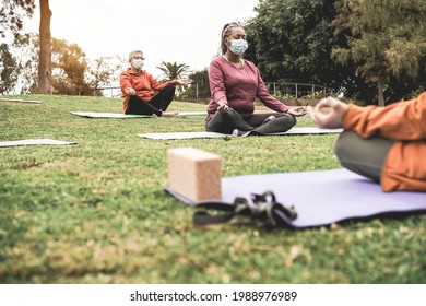 People Doing Yoga Class Outdoor Sitting On Grass While Wearing Safety Masks During Coronavirus Outbreak - Main Focus On Left Senior Woman Face