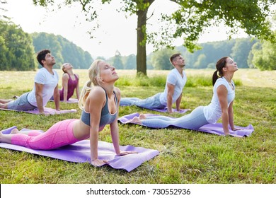 People doing yoga exercise in park in wellness relaxation seminar 