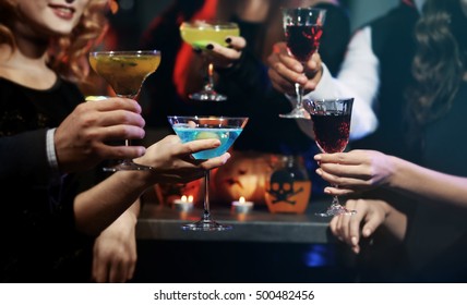 People drinking colorful cocktails at Halloween party, closeup