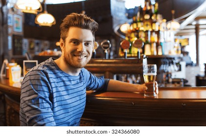 People, Drinks, Alcohol And Leisure Concept - Happy Young Man Drinking Beer At Bar Or Pub