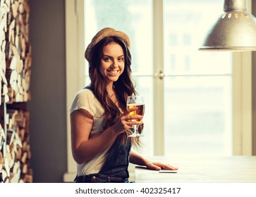 people, drinks, alcohol and leisure concept - happy young redhead woman drinking beer at bar or pub