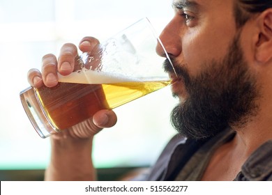 People, Drinks, Alcohol And Leisure Concept - Close Up Of Young Man Drinking Beer From Glass At Bar Or Pub