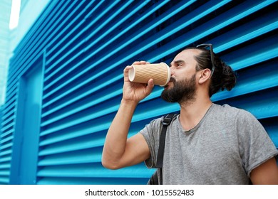 people, drinks and lifestyle concept - man drinking coffee from disposable paper cup on street over ribbed blue wall background - Powered by Shutterstock