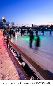 People at dusk skating on The Quays Skating Rink in the Quays of the Old Port in Montreal on a cold January evening 