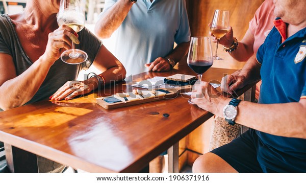 People eat cheese and drink wine in a\
restaurant on a terrace on a sunny day. A table in a restaurant\
with a cheese plate, bread, full of\
visitors.