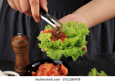 People Eating Bossam (bo Ssam) Or Korean Style Boiled Pork Belly Along With Salted Napa Cabbage Leaves And Spicy Radish Salad And Bean Curd. Enjoy Korean Dish Theme.