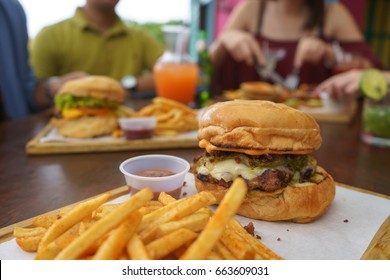 People Eating Burger In A Restaurant With Friends In Background