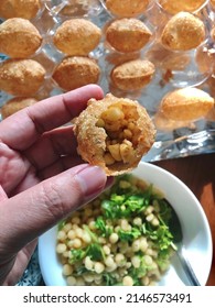 People eating Pani Puri, hand holding round crispy hollow puri (deep-fried dough ball) stuffed with mashed potato and boiled chickpeas, filled with pani (mixture of spicy tangy water and sweet chutney