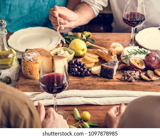 People eating a platter of cheese with seasonal fruits and wine - Powered by Shutterstock