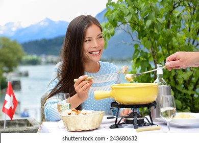 People Eating Swiss Cheese Fondue Having Dinner In Switzerland By Lake In Alps. Woman Eating Local Food Having Fun On Travel In Europe. Romantic Couple Outdoors In Summer.