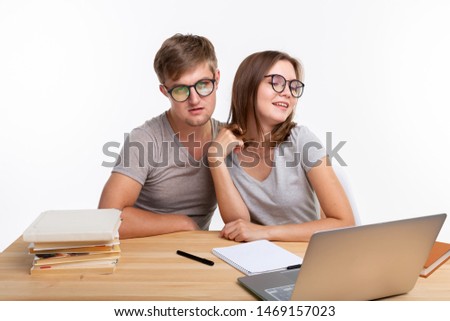 People and education concept - Two fallen in love funny students sitting at the wooden table with laptop and books
