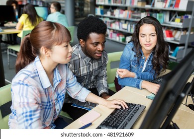 people, education, technology and school concept - group of international students with computers at library in university