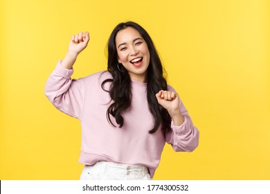People emotions, lifestyle leisure and beauty concept. Upbeat happy and cheerful asian girl dancing and having fun, partying, moving rhythm music and smiling over yellow background - Shutterstock ID 1774300532