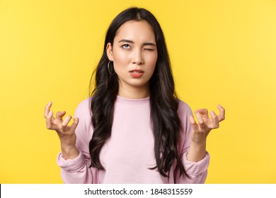 People Emotions, Lifestyle Leisure And Beauty Concept. Annoyed And Pissed-off Asian Girl Eye Roll From Anger, Clench Fists Mad And Bothered With Something Stupid, Yellow Background