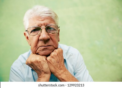 People And Emotions, Portrait Of Depressed Senior Hispanic Man With Glasses Looking At Camera, Leaning With Hands On Chin. Copy Space