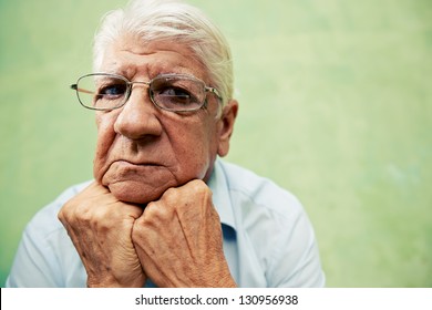 people and emotions, portrait of depressed senior hispanic man with glasses looking at camera, leaning with hands on chin. Copy space - Powered by Shutterstock