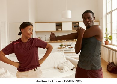 People, Energy, Activity, Fitness And Home Training Concept. Portrait Of Adorable Young Mixed Race Couple Exercising Indoors, Having Fun, Warming Up Body In The Morning After Awakening, Fooling Around