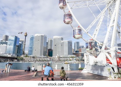 People enjoy sitting at the Darling Harbour with part of Ferris Wheel - Shutterstock ID 456311359