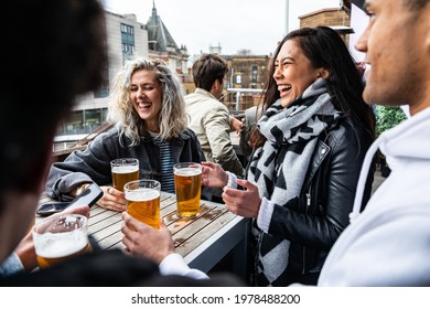 People enjoying a beer together at pub brewery - Happy laughing man and women talking and raising pint glass - Lifestyle and drink concepts in London