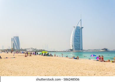 People Are Enjoying A Sunny Day On A Beach In Front Of The Burj Al Arab Hotel In Dubai, UAE