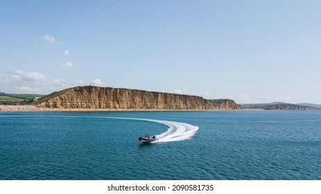 People Enjoying A Thrilling Rib Charter Ride On A Speed Boat In Front Of The Famous West Bay Cliffs On The Jurassic Coast