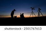 People enjoying watching and stargazing with astronomy telescopes outdoors in nature, observing planets, Moon and other celestial objects.