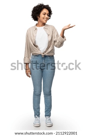 people, ethnicity and portrait concept - happy smiling woman in shirt and jeans holding something imaginary on her hand over white background