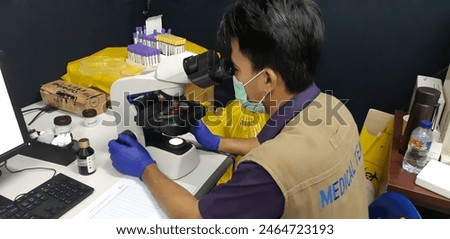 people are examining in a microscope