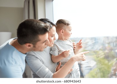 People And Family Concept - Happy Mother, Father And Little Son Looking Through Window At Home