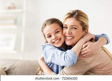 people and family concept - happy smiling girl with mother hugging on sofa at home - Powered by Shutterstock