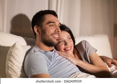 Menschen, Familien- und Freizeitkonzept - glückliches Ehepaar, das nachts im Bett zusieht