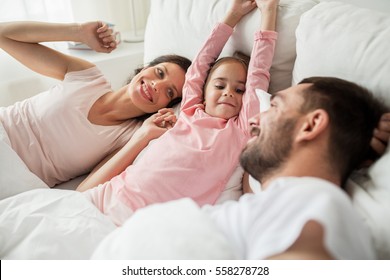 People, Family And Morning Concept - Happy Child With Parents Waking Up In Bed At Home