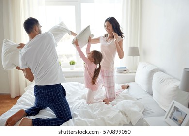 People, Family And Morning Concept - Happy Child With Parents Having Pillow Fight In Bed At Home