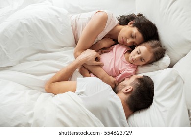 People, Family And Rest Concept - Happy Child With Parents Sleeping In Bed At Home