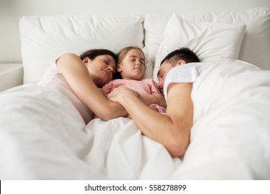 People, Family And Rest Concept - Happy Child With Parents Sleeping In Bed At Home