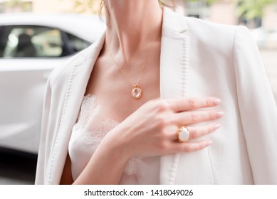 People, fashion, jewelry and luxury concept, closeup of woman wearing luxury jewelry standing near expensive car on the street. Color gemstone ring and pendant with colored diamonds and gemstones