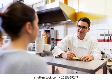 people, fast food and cooking concept - happy smiling chef at restaurant writing order and customer - Powered by Shutterstock