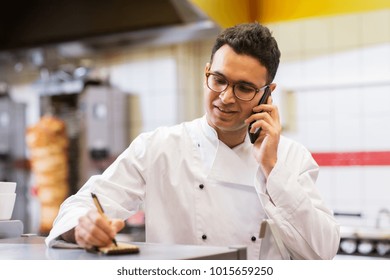 people, fast food and cooking concept - chef at kebab shop writing order and calling on smartphone - Powered by Shutterstock