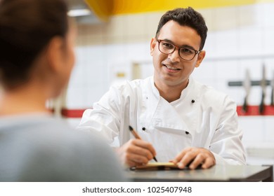 people, fast food and cooking concept - happy smiling chef at restaurant writing order and customer - Powered by Shutterstock