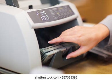 People, Finance And Cash Concept - Clerk Hand Counting Dollars With Electronic Money Counter Machine At Bank Office Or Currency Exchanger