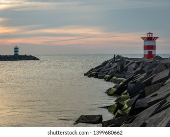 People are fishing near the lighthouses on the piers of Scheveningen.